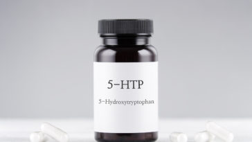 nutritional supplement 5-HTP hydroxytryptophan, bottle and capsules on gray