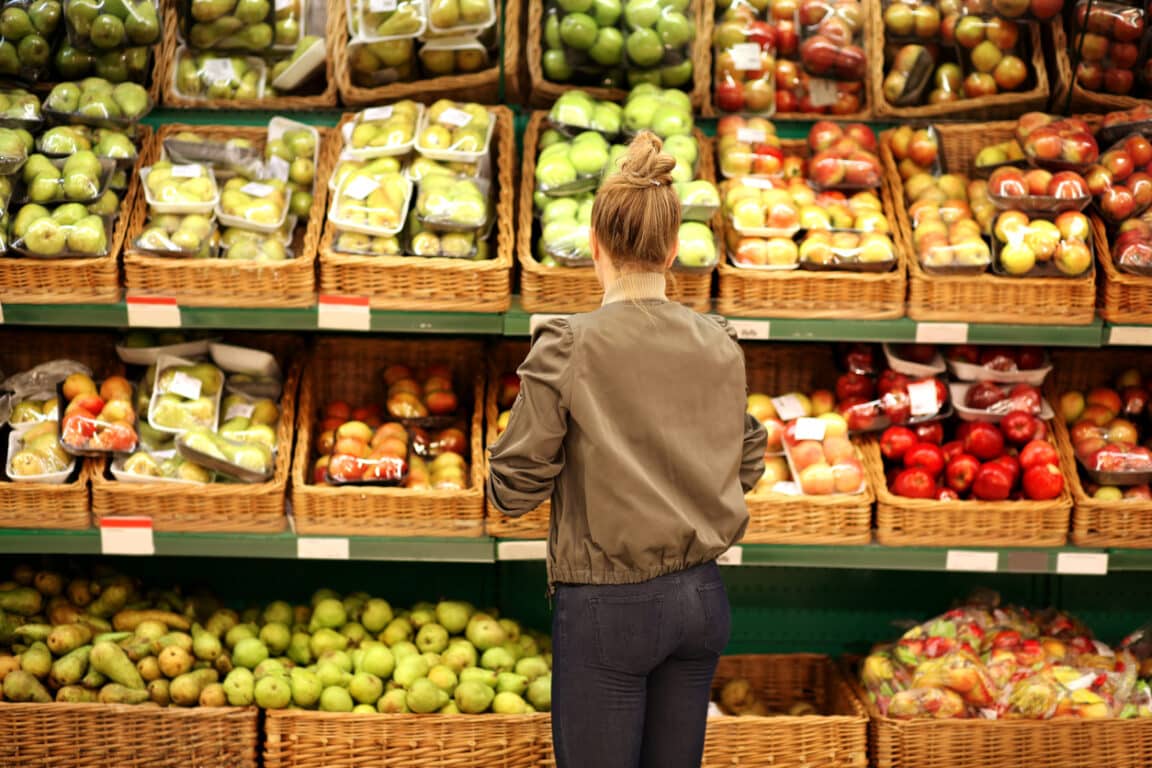 femme choisir fruits pesticides rayon supermarché courses
