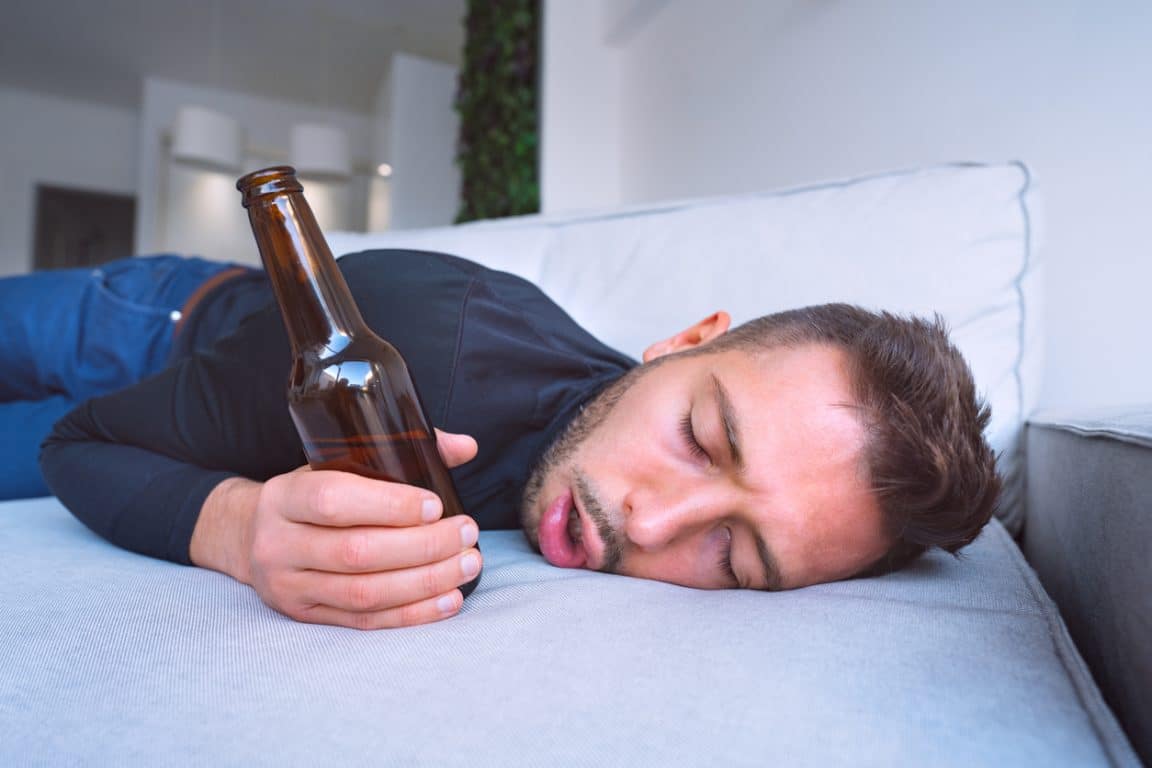 Jeune homme ivre avec la bouche ouverte et la bouteille de bière ivresse gueule de bois lendemain difficile homme bourré trop d'alcool taux d'alcoolémie élevé
