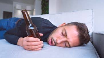 Jeune homme ivre avec la bouche ouverte et la bouteille de bière ivresse gueule de bois lendemain difficile homme bourré trop d'alcool taux d'alcoolémie élevé