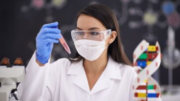 Une scientifique examinant un échantillon d'ADN à côté d'un modèle d'hélice d'ADN